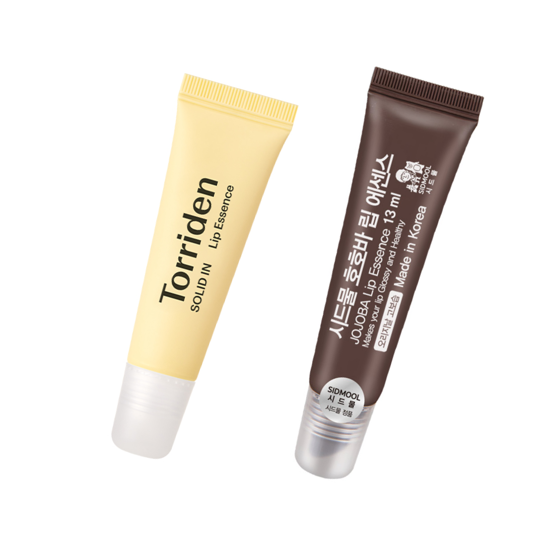 Two Korean lip essences are displayed side by side: a yellow Torriden Solid-In Lip Essence tube and a brown SIDMOOL Jojoba Lip Essence tube. Both come in soft squeeze packaging with clear applicator tips, highlighting their moisturizing, glossy lip-care formulas.